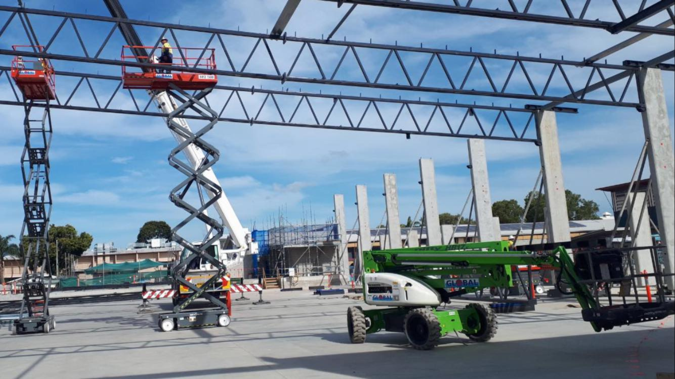 Two scissor lifts at height and a parked boom lift